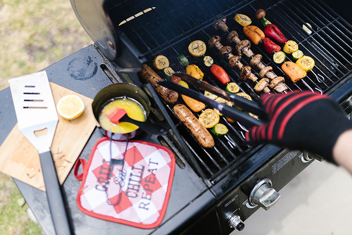 Person grilling meat with vegetables, enjoying a fun hobby outdoors.
