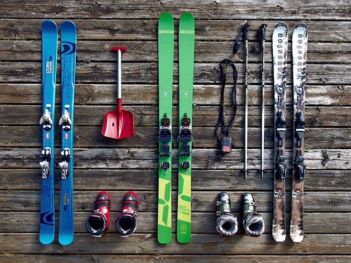 Flatlay of skiing equipment including skis, poles, boots, and a shovel on wooden background, showcasing fun hobbies to try.