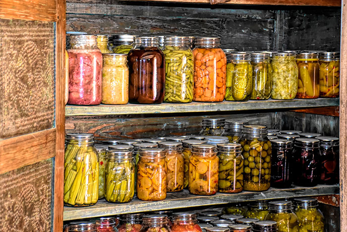 Jars of preserved food on a wooden shelf, showcasing fun hobbies to pursue in home canning and food preservation.