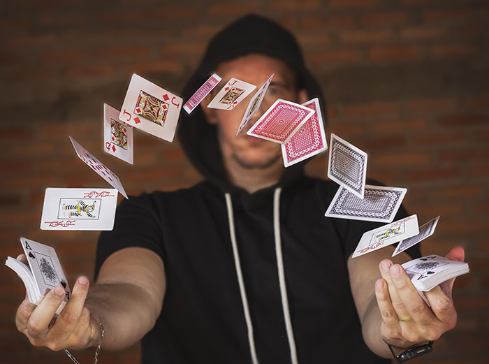 Man showcasing card trick, demonstrating fun hobby with playing cards in motion.