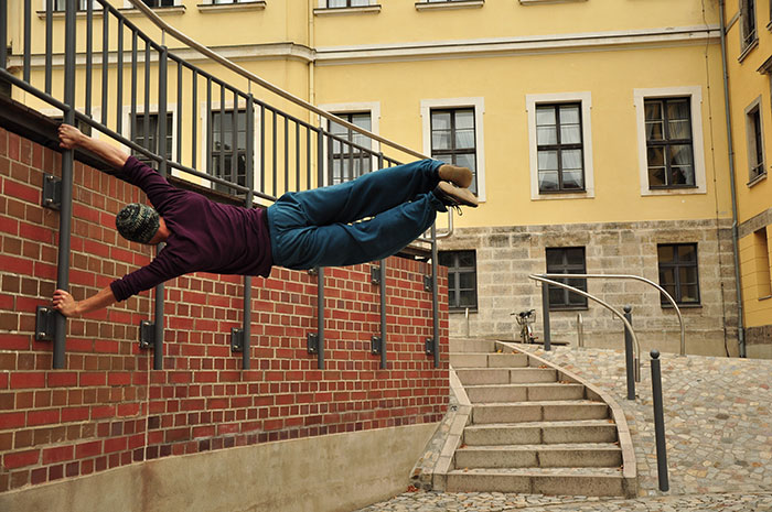 Man performing parkour on urban railings, illustrating fun hobbies to pursue in an outdoor setting.