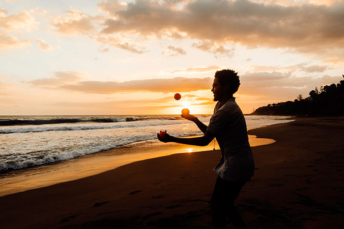 Man juggling on a beach at sunset, exploring fun hobbies.