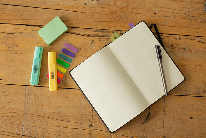 Open notebook with blank pages and pen on wooden table, suggesting a fun hobby idea.
