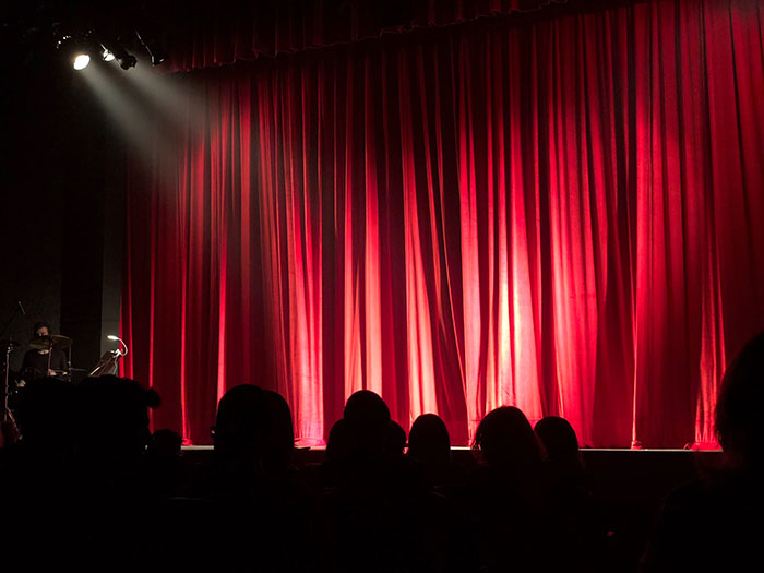 Red theater curtains illuminated on stage, a scene depicting the backdrop for performing arts hobbies.