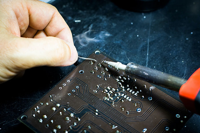Person soldering a circuit board, illustrating an engaging engineering hobby activity.