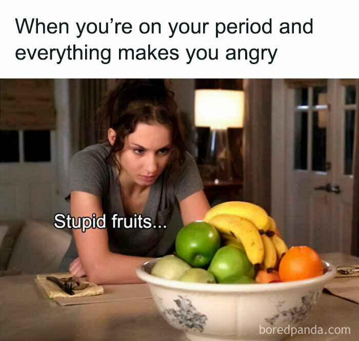 Woman angrily staring at a bowl of fruit, conveying a spicy meme about emotional reactions during menstruation.