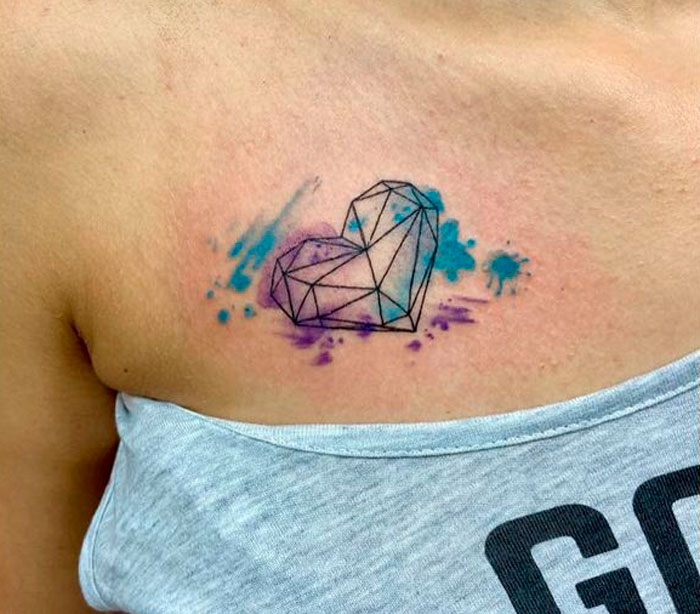 Geometric heart tattoo with watercolor splash on shoulder.