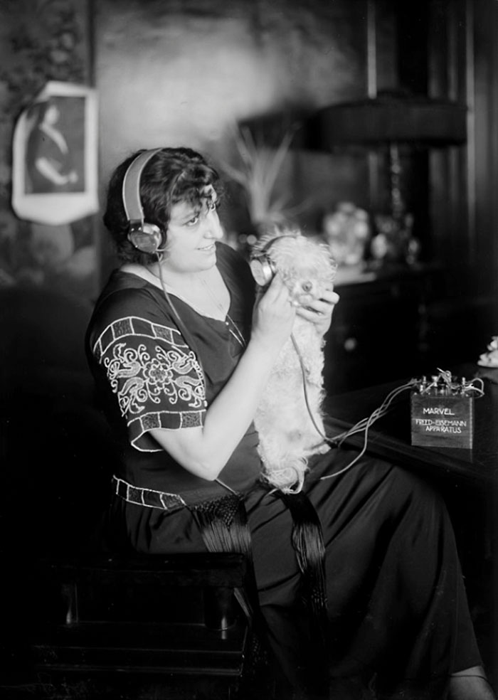 Italian Opera Singer Claudia Muzio Listening To The Radio With Headphones While Holding A Dog Who Also Has Headphones