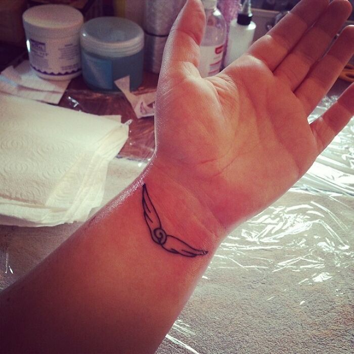 Wrist tattoo of a simple wing design, popular as a timeless accessory.