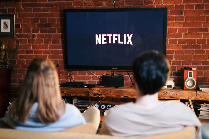 Two people watching Netflix, sitting in a cozy brick-walled living room.