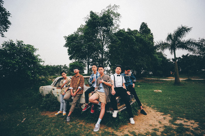 Millennials posing in stylish outfits by a vintage car in a park, showcasing casual fashion.