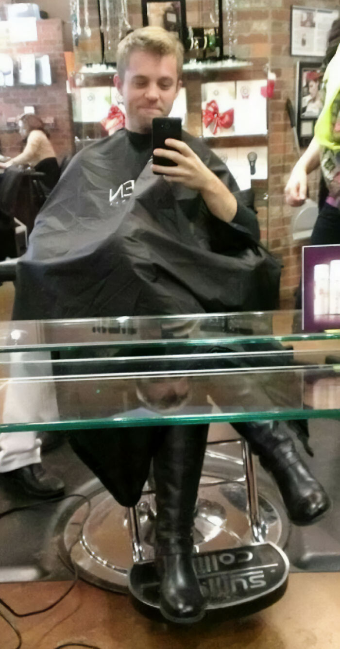 Funny mirror reflection of a man with woman legs in a barber shop 