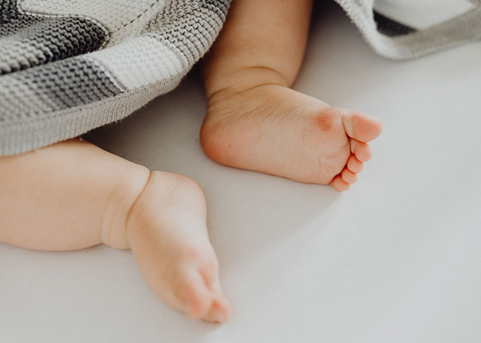 Baby's feet peeking from under a blanket, symbolizing grandkid's footprint.