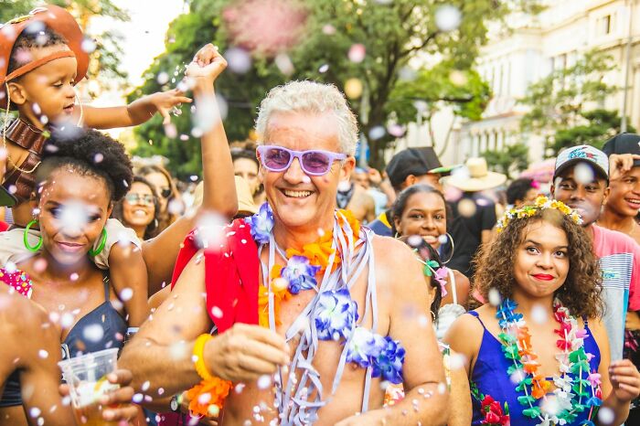 man in a purple sunglasses between people wearing hawaiian decoration