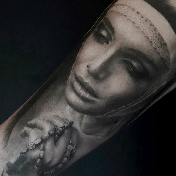 Realistic tattoo of a praying woman, showcasing intricate facial details and hands holding a rosary.