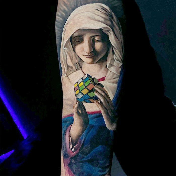 Realistic tattoo of a serene woman solving a Rubik's Cube, showcasing exceptional artistic detail.
