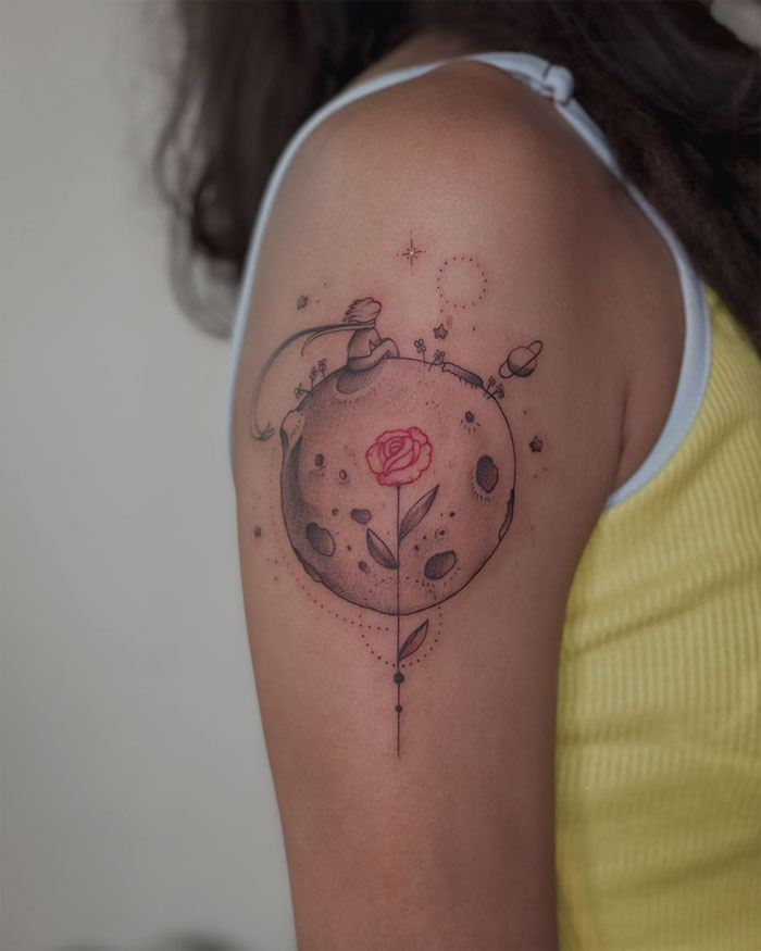 Red ink tattoo of a planet with a rose on an arm, showcasing creative tattoo design.