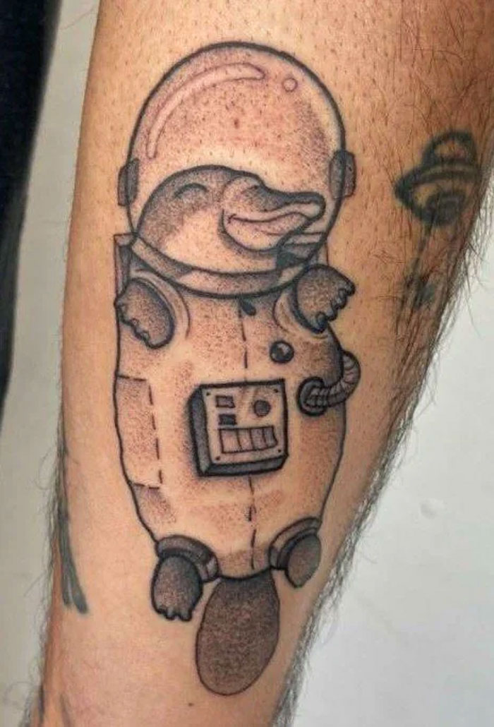 Cute platypus in a spacesuit tattoo on arm, showcasing cool space tattoo art.