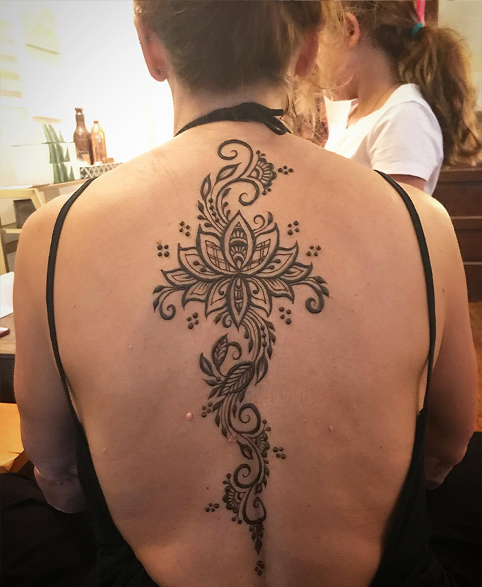 Elegant spine tattoo with intricate floral design on a woman's back.