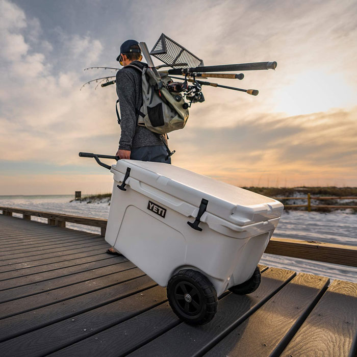 Man carrying portable wheeled cooler 