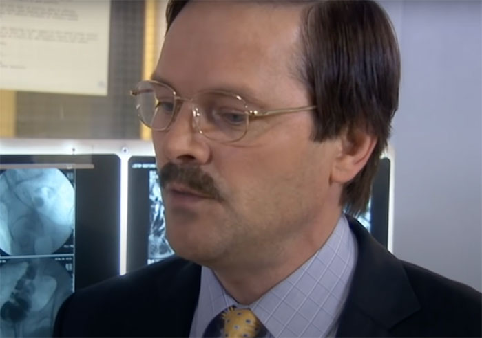 Alan wearing glasses and suit in Green Wing