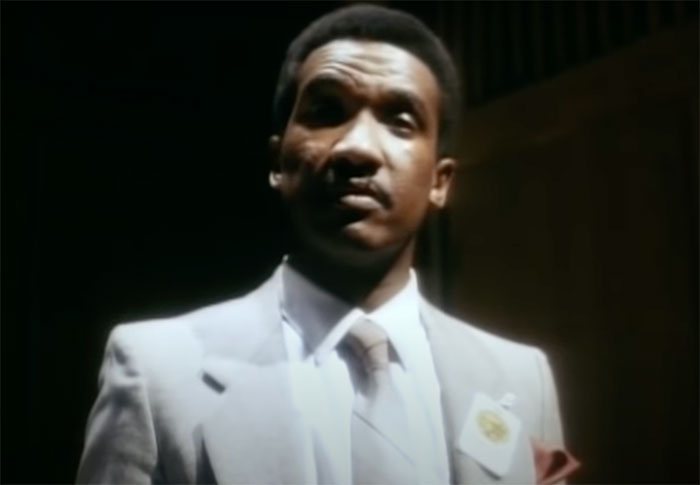 Person wearing white suit standing in Cop Rock