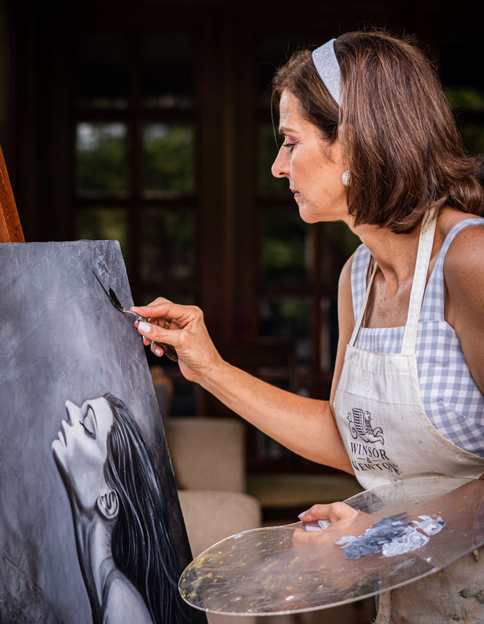Woman over 50 painting a grayscale portrait, sharing life advice and wisdom that younger people haven’t realized yet