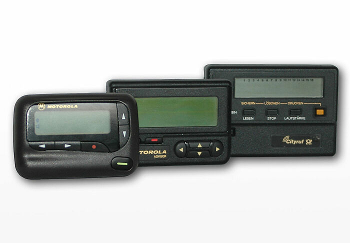 Three old gadgets including Motorola pagers displayed side by side, showcasing vintage communication devices.