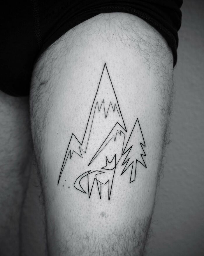 Single line tattoo of mountains, trees, and a wolf on a person's thigh, showcasing captivating artistry.