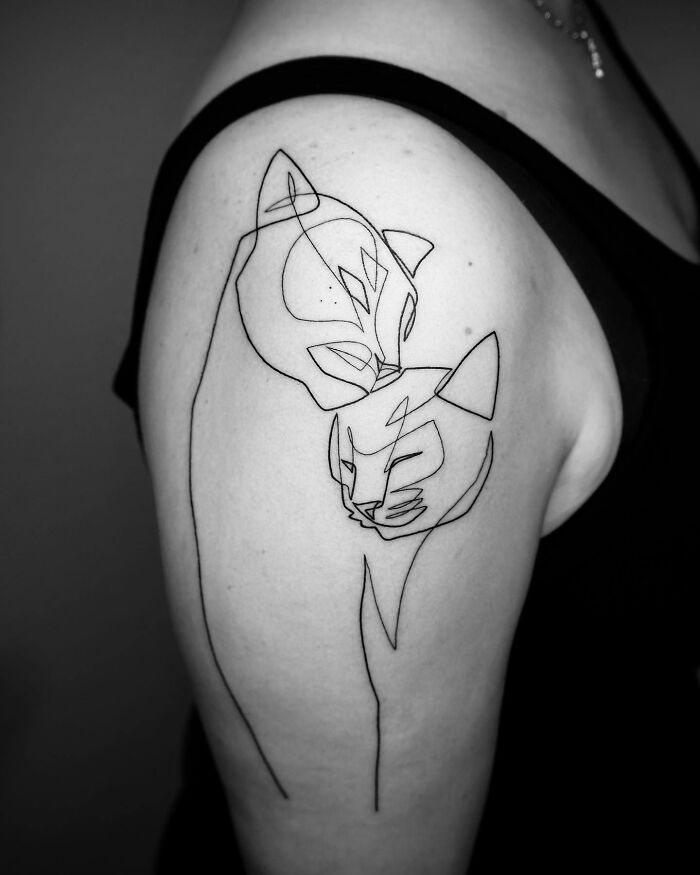 Single line tattoo of two cats on an upper arm, showcasing captivating minimalist art.