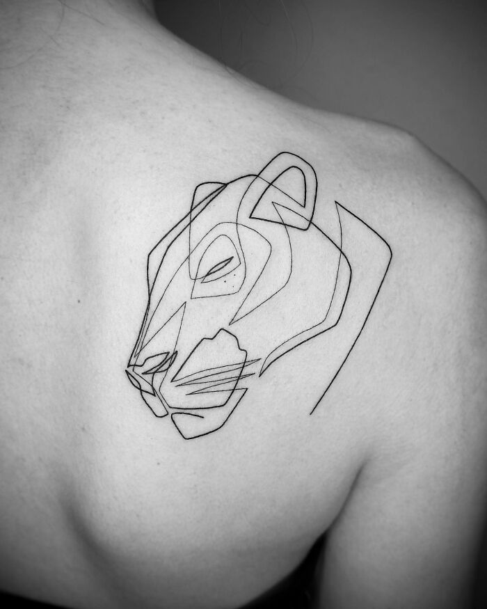 Single line tattoo of a lion's face on a person's shoulder, showcasing captivating tattoo artistry.