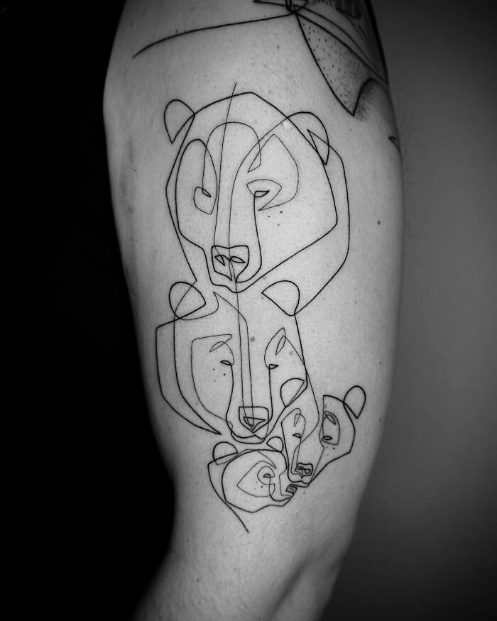 Single line tattoo of abstract bear faces on an individual's arm.