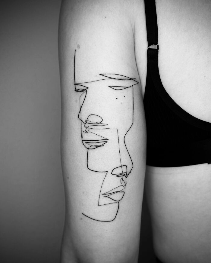 Single line tattoo art depicting abstract faces on a person's arm.