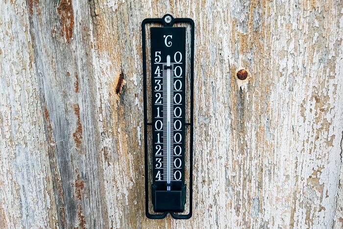 Outdoor thermometer on a weathered wooden wall illustrating flight attendants sharing what annoys them.