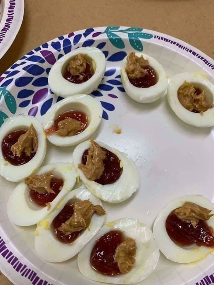 Hard-boiled eggs topped with peanut butter and jelly on a paper plate, presenting a horrible food combination.