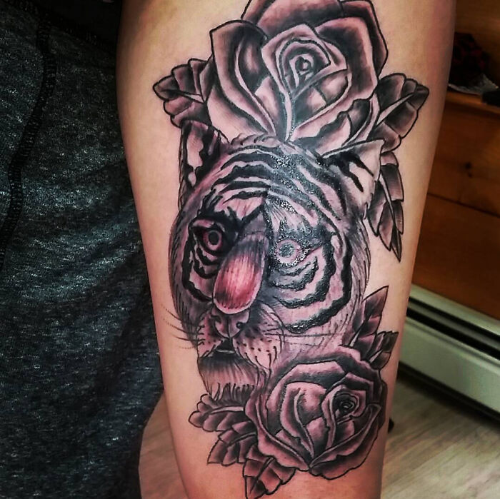 Tattoo fail of a tiger with distorted face and roses, showcasing an epic and humorous tattoo mistake on the arm.