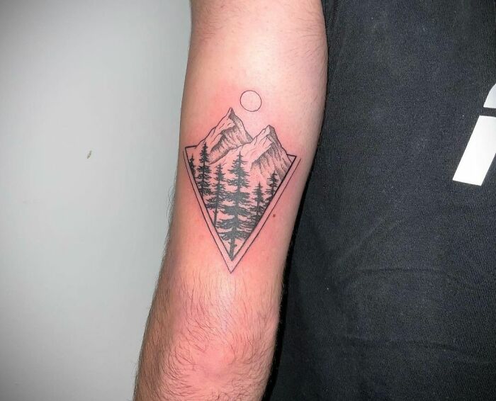 Nature tattoo depicting mountains and trees on a person's arm.