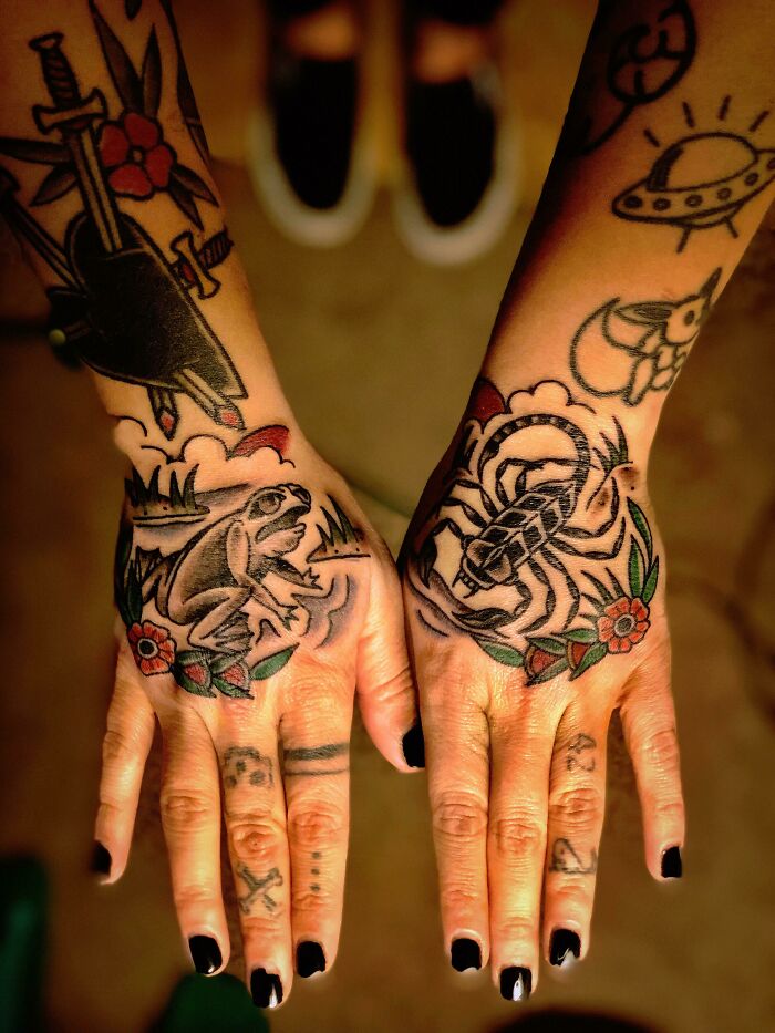 Hands showcasing nature tattoos with a frog and scorpion design.