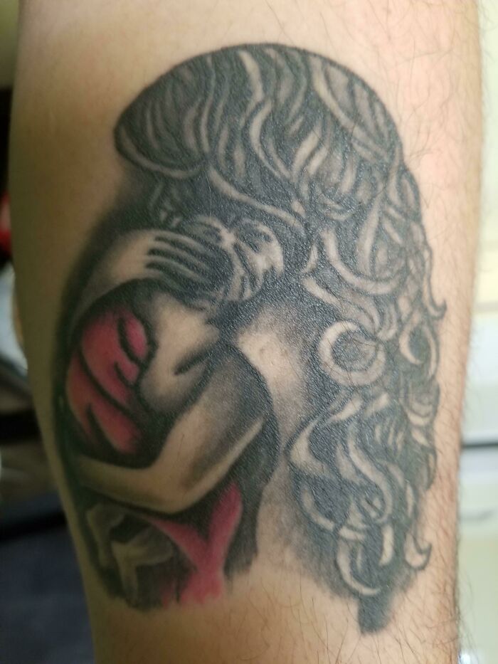 Tattoo fail showing a poorly executed woman with distorted features and blurry black and red ink on skin.