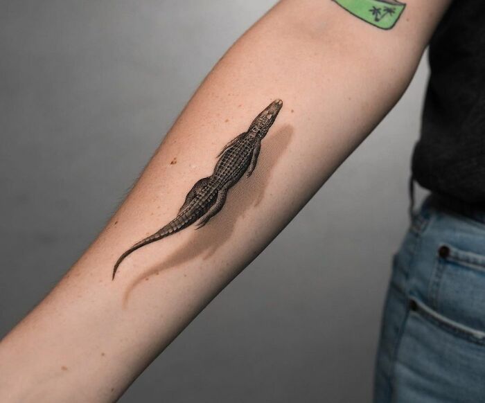 Optical illusion tattoo of a crocodile on an arm, showcasing eye and mind-bending design artistry.
