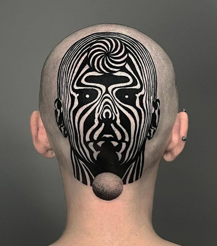 Optical illusion tattoo on the back of a shaved head creates a mind-bending face design.