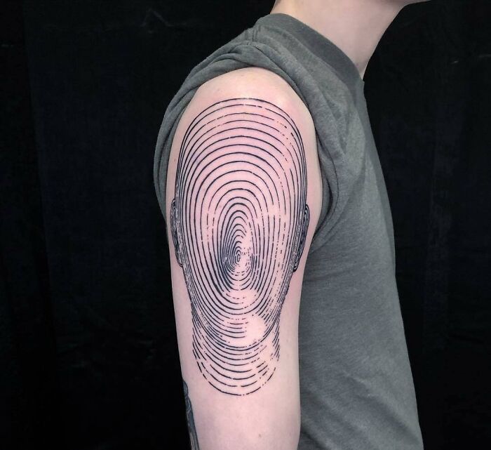 Optical illusion tattoo on arm with concentric lines creating an eye-bending effect.