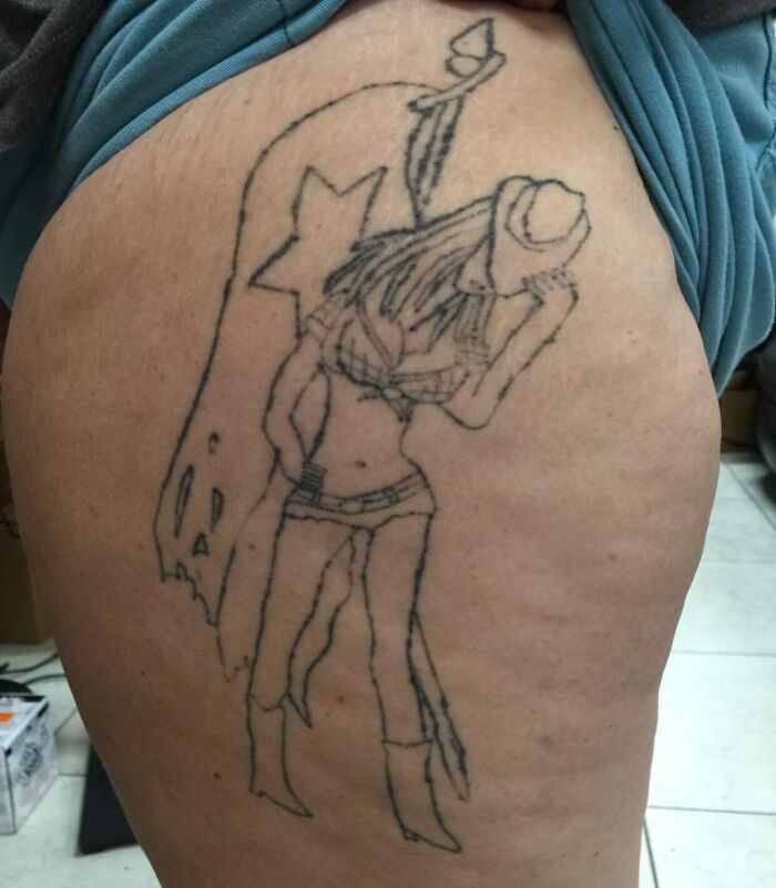Tattoo fail of a poorly drawn woman with a flag on a person's thigh showing a badly executed tattoo design.