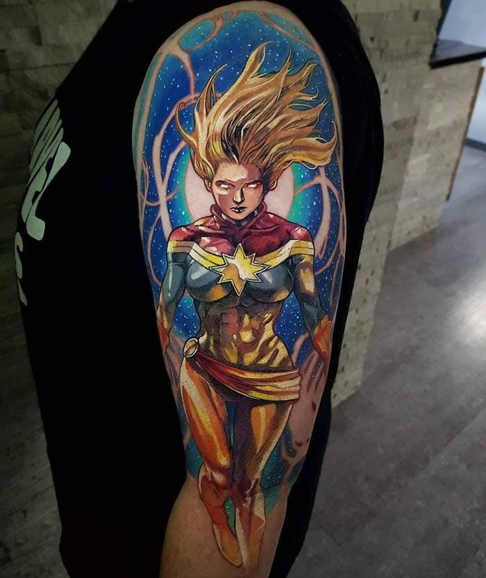 Marvel tattoo of superhero Captain Marvel on an arm, featuring vibrant colors and dynamic design.