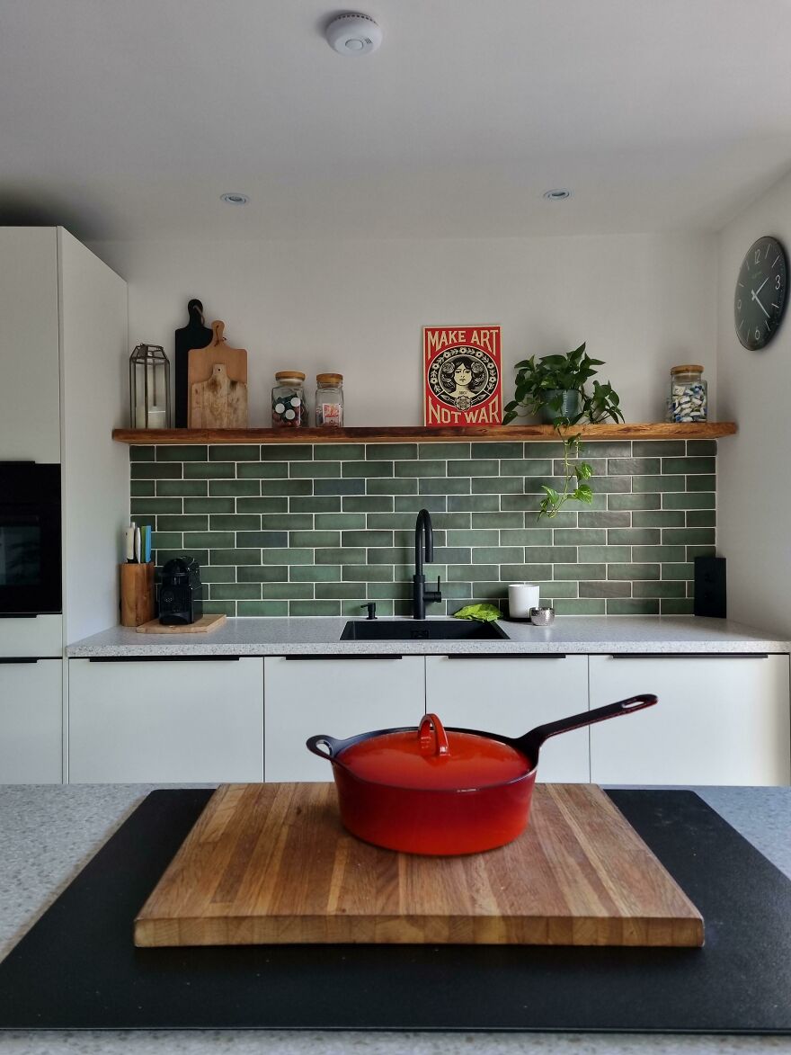 Green kitchen tiles, red pan on the stove 
