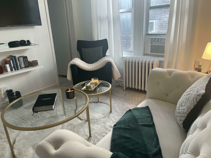 White couch next to a glass coffee table and black chair 