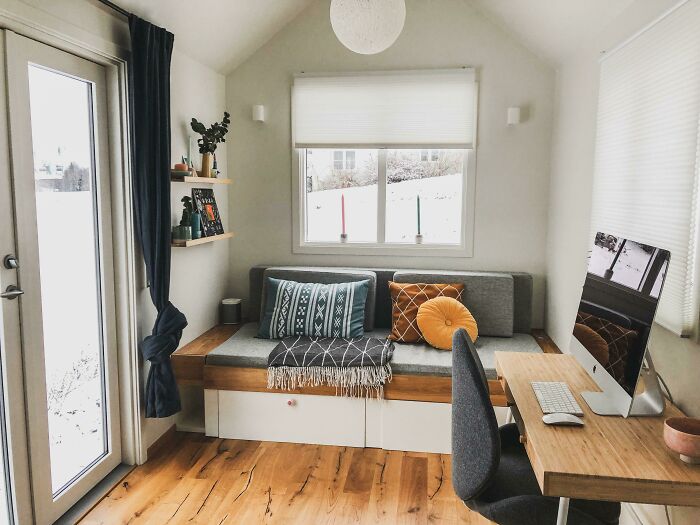 Cozy and bright tiny house living area with a modern desk, computer, and stylish window seat.