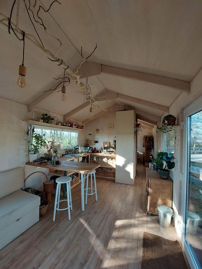 Bright tiny house kitchen with brown wooden cabinets, white walls, and natural light creating a cozy tiny house design.