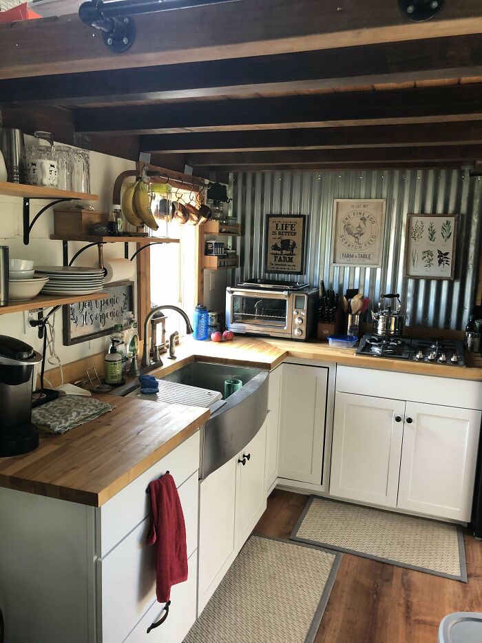 Cozy tiny house kitchen with wood counters, open shelving, and farmhouse sink.