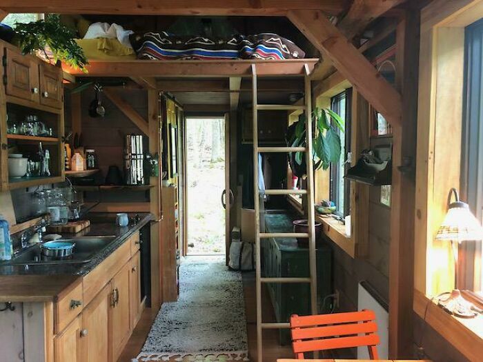 Cozy tiny house kitchen with brown cabinets and black countertops featuring rustic wooden accents and compact design.